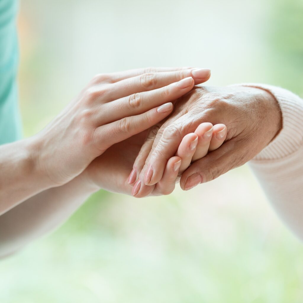 Caretaker massaging pensioner's hand
